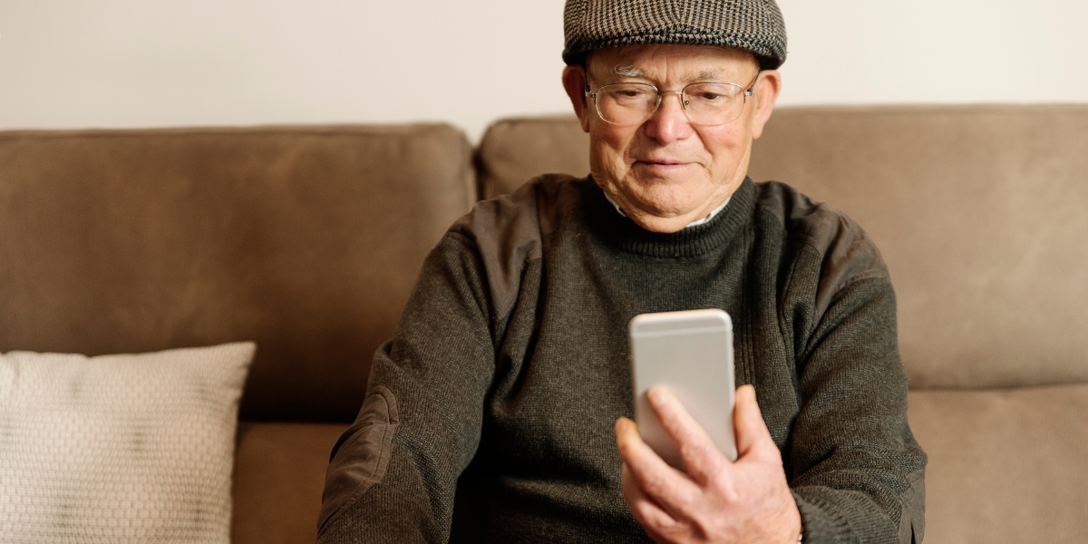 Older man on smart phone sitting on couch.